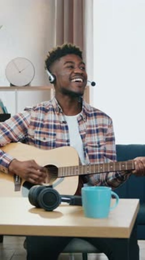 Smiling Man Plays Guitar with Headphones Indoors
