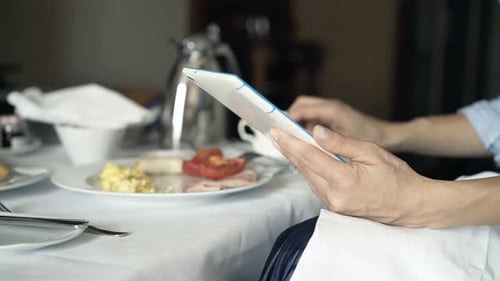 Businesswoman Hands with Tablet Computer by the Table During Breakfast Alone