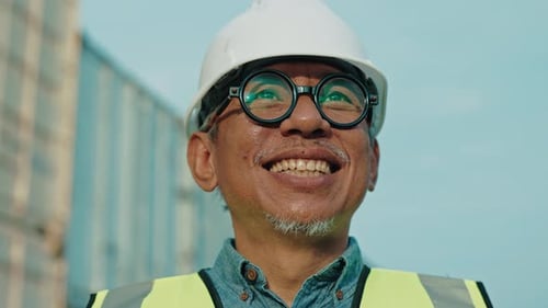 Portrait Of Positive Handsome Industrial Engineer With Smile Standing Near Container Terminal