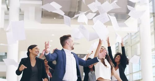 4k video footage of a group of businesspeople throwing paperwork and high fiving in their workplace