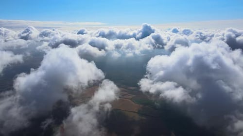 Aerial View From Airplane Window at High Altitude of Earth Covered with Puffy Cumulus Clouds Forming