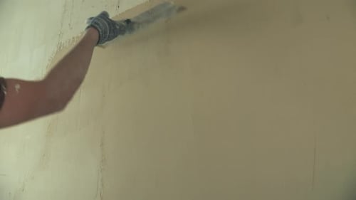 Gloved Hand Smoothing Plaster on Wall with Tool