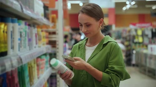 Woman Using Smartphone Scanning Product in Supermarket