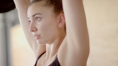 Focused unaltered caucasian woman free weight training at gym lifting barbell, in slow motion