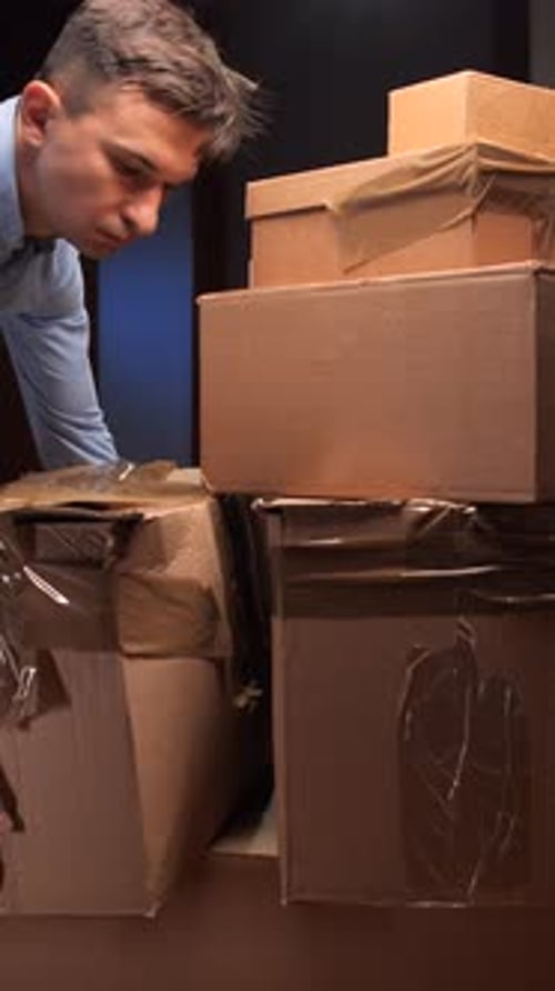 Man putting cardboard boxes down in dark room