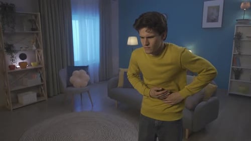 Man Holding Stomach In Home, Experiencing Pain