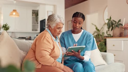 Senior Woman and Nurse Discussing Tablet at Home