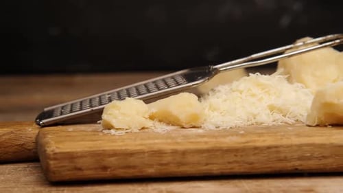 Fromage râpé à côté de morceaux de parmesan