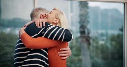 Mature Couple Embracing at Home by a Window