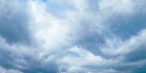 Fluffy grey clouds floating in the atmosphere. Overcast gloomy sky from low angle perspective.