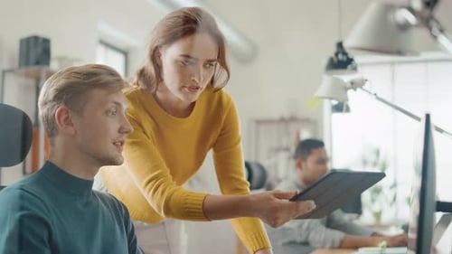 Colleagues Discussing Work at Desk in Modern Office