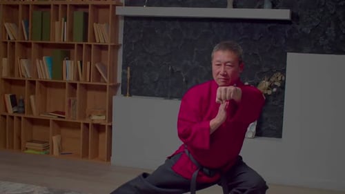 Konzentrierter reifer Taekwondo-Meister in Uniform, trainiert Schlagtechniken