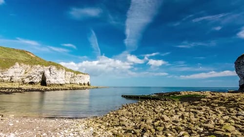 Time lapse of a beach in the day time while sun is shining and clouds are moving in the blue sky whi