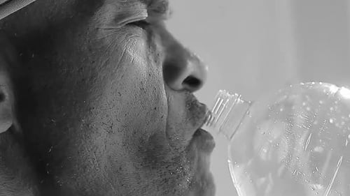 Close-Up of Man Drinking Water from Plastic Bottle