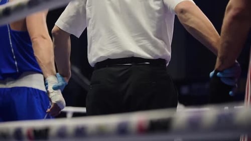 The judge raises his hand to a man in the boxing ring. Referee declaring a winner of a fight