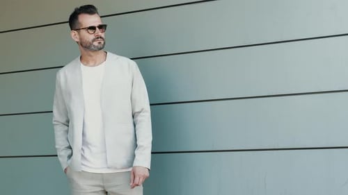 Stylish Man Poses Confidently Against Modern Urban Wall