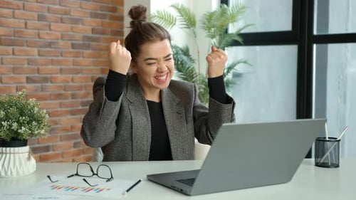 Joyful Businesswoman Celebrating a Major Achievement at Her Office Workspace