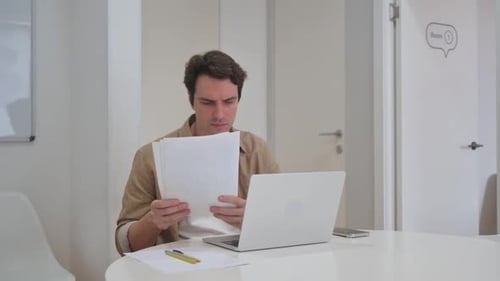Young Adult Male Working With Documents in Office