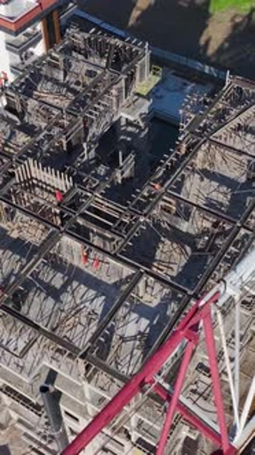 Vídeo vertical: Zona de construcción capturada verticalmente con trabajadores completando una variedad de tareas y