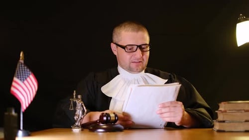 Judge Reading Documents in Courtroom at Night