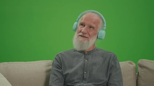 Green Screen An Old Man with a Gray Beard Listens to Music on Headphones