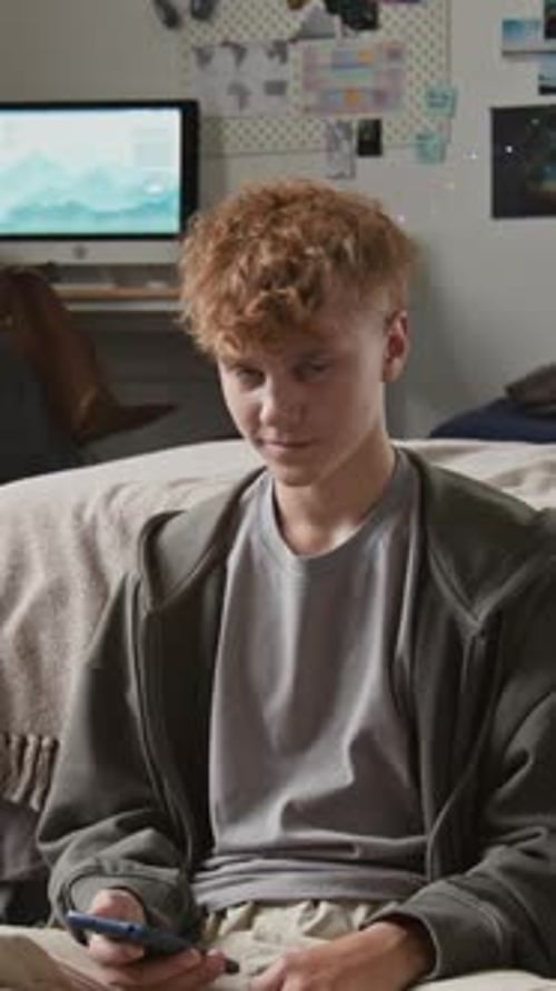 Smiling Teenager Using Smartphone in Bedroom Setting