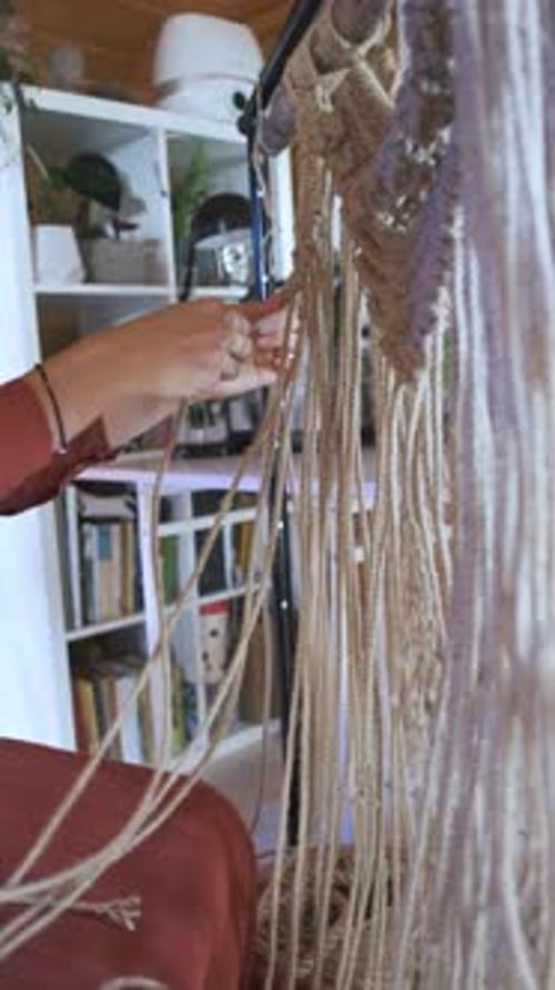 close-up women weaving macrame from a rope at home