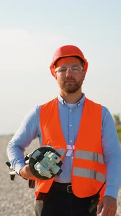 Confident Male Surveyor Holding Theodolite on a Construction Site