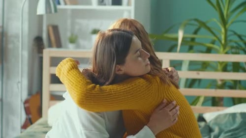 Women Embracing Indoors in a Bedroom