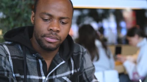 portrait of a dark-skinned man eating french fries at the food court