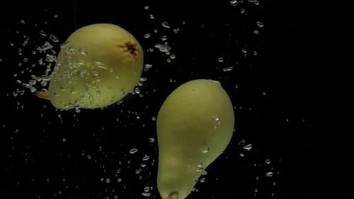 Slow Motion Two Pear Falling Into Transparent Water on Black Background
