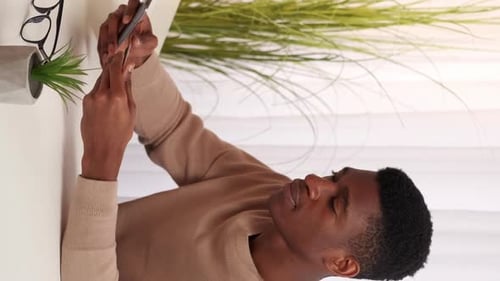 Young Adult Using Phone Indoors at Desk