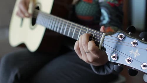 Musician's Fingers Skillfully Playing Acoustic Guitar Chords Creating Melodic Sound with Intricate