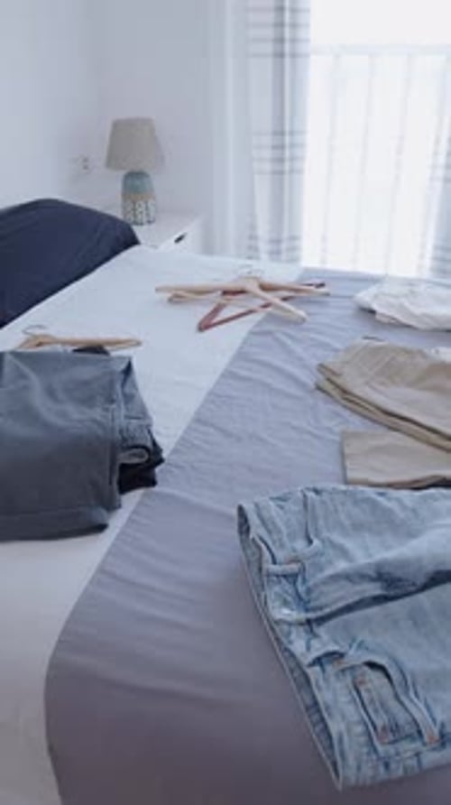 Plusieurs vêtements sur le lit dans une pièce lumineuse