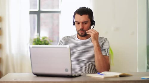 Man Working At Laptop Wearing Headset