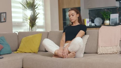 Woman Meditating on Couch in Living Room