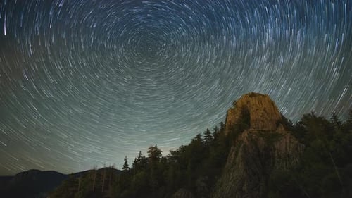 Berggipfel mit Fichtenwäldern an den Hängen vor dem Hintergrund des Sternenhimmels