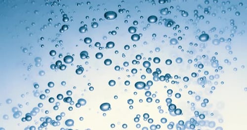 Many water bubbles in blue water close up, abstract water wave with bubbles in slow motion.