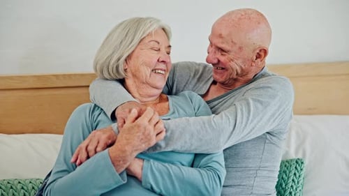 Senior Couple Embrace on Bed Smiling Tenderly