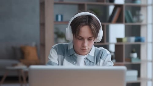Teen With Headphones Using Laptop at Home