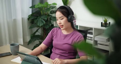 Young businesswoman with big earphones video call on laptop working from home.