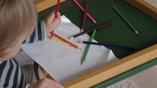 Child Drawing with Colored Pencils at Table