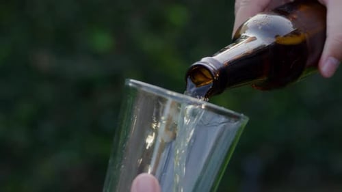 Pouring refreshing beer from bottle into glass