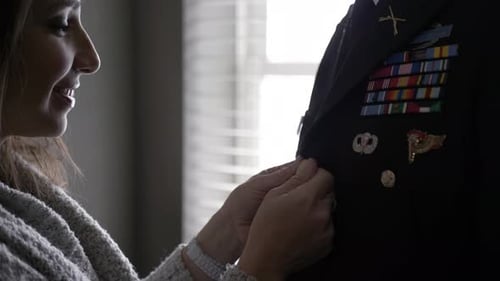 Woman Adjusting Military Uniform of Man in Home