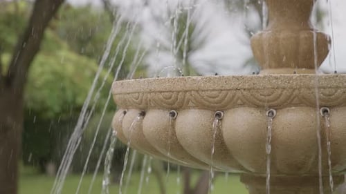 Stone garden fountain with flowing water streams close up