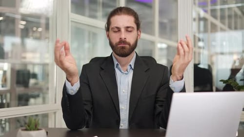 Bearded Business Man Folding Fingers in Mudra Gesture While Meditating in Office