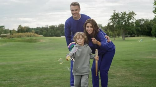 A Family Blows Soap Bubbles Together in the Park
