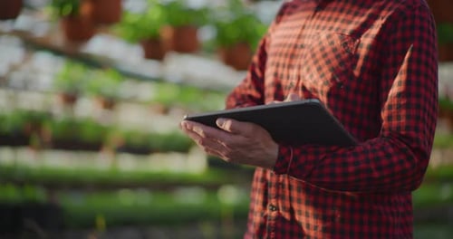 Gardener Using Digital Tablet in Greenhouse