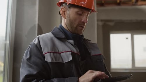 Foreman Reviewing Building Plans on Tablet at Unfinished Site