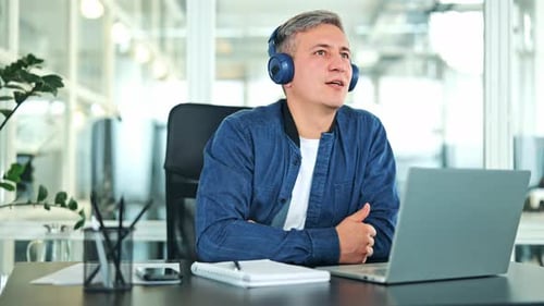 Man Working At Desk With Laptop And Headphones